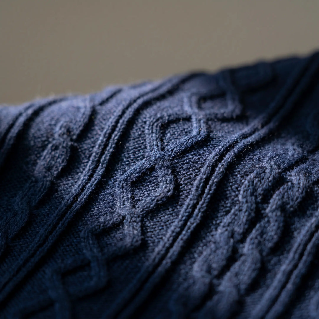 Close-up view of a dark navy blue knitted polo shirt showcasing its intricate diamond and vertical rib pattern with a fine-gauge texture.