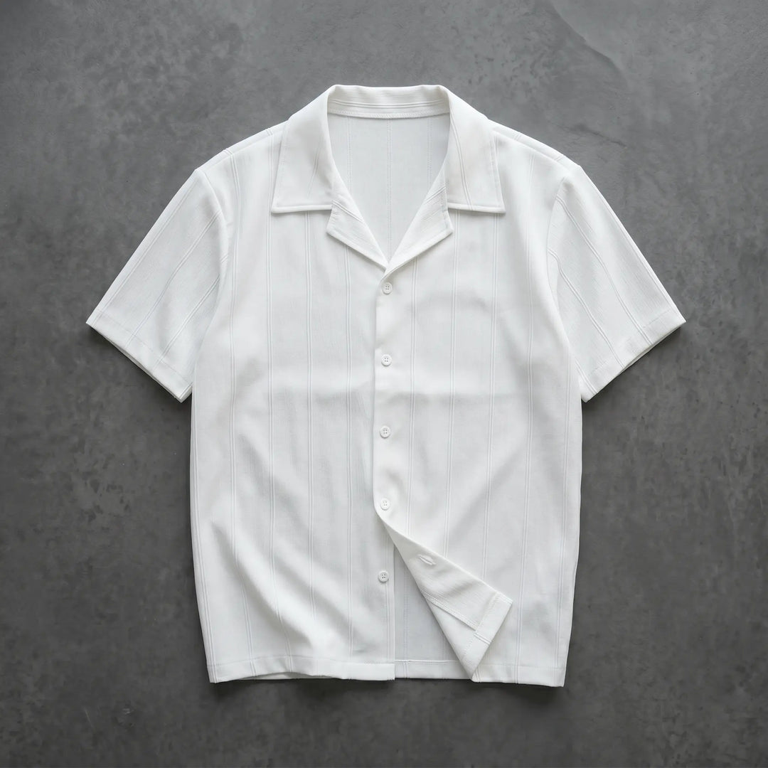 Crisp white Kaelen short-sleeve Cuban collar shirt featuring subtle vertical ribbing and tonal matte buttons, laid flat for a clear front view.