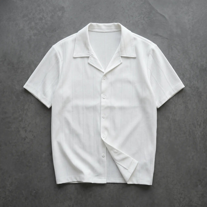 Crisp white Kaelen short-sleeve Cuban collar shirt featuring subtle vertical ribbing and tonal matte buttons, laid flat for a clear front view.