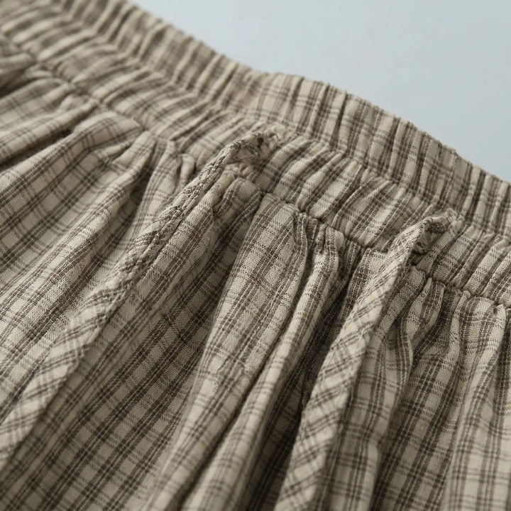 Close-up view of Zelphyr wide-leg plaid trousers, showcasing the fine oat beige check pattern and a fully elasticated, gathered waistband.